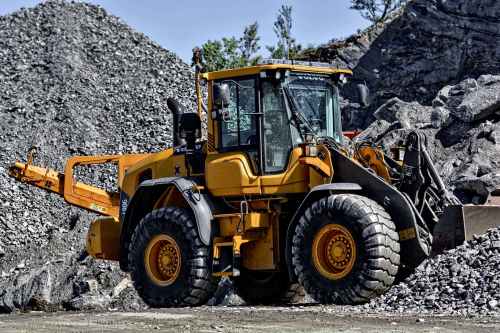 orange and black tractor next to piles of rocks